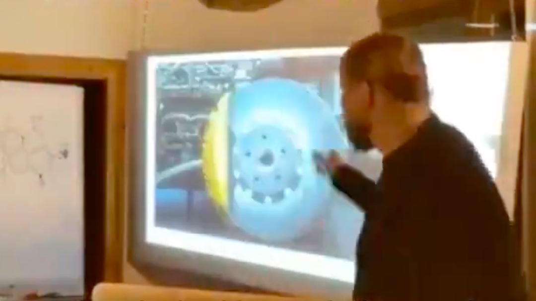 5. Dr. Noack points to an image of brake pads made from carbon on the screen.